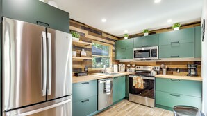Una cocina moderna con electrodomésticos de acero inoxidable, armarios azul turquesa y un protector contra salpicaduras de madera.