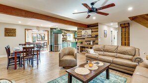 Amplia sala de estar con mesa de comedor de madera, sofá de cuero y ventilador de techo.