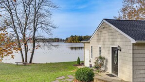 Une maison avec un chemin de pierre menant à une porte, un petit jardin et une vue sur un lac.