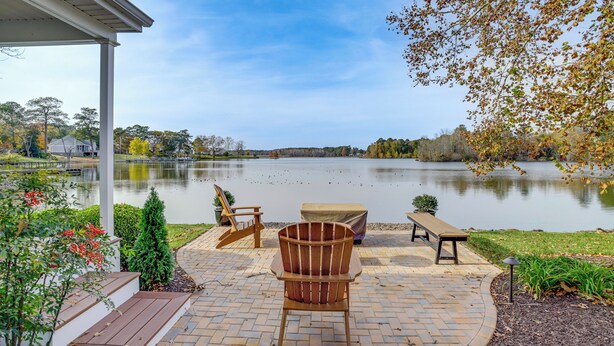 Une terrasse avec des meubles d’extérieur, un espace salon abrité et une vue sur un lac.