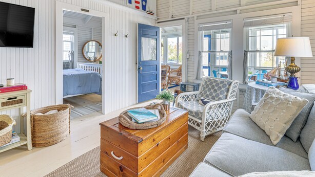 A room with a wooden chest, wicker baskets, a sofa, and a television. - Steps to Beach: Timeless Lower Cape Cottage (Brewster)