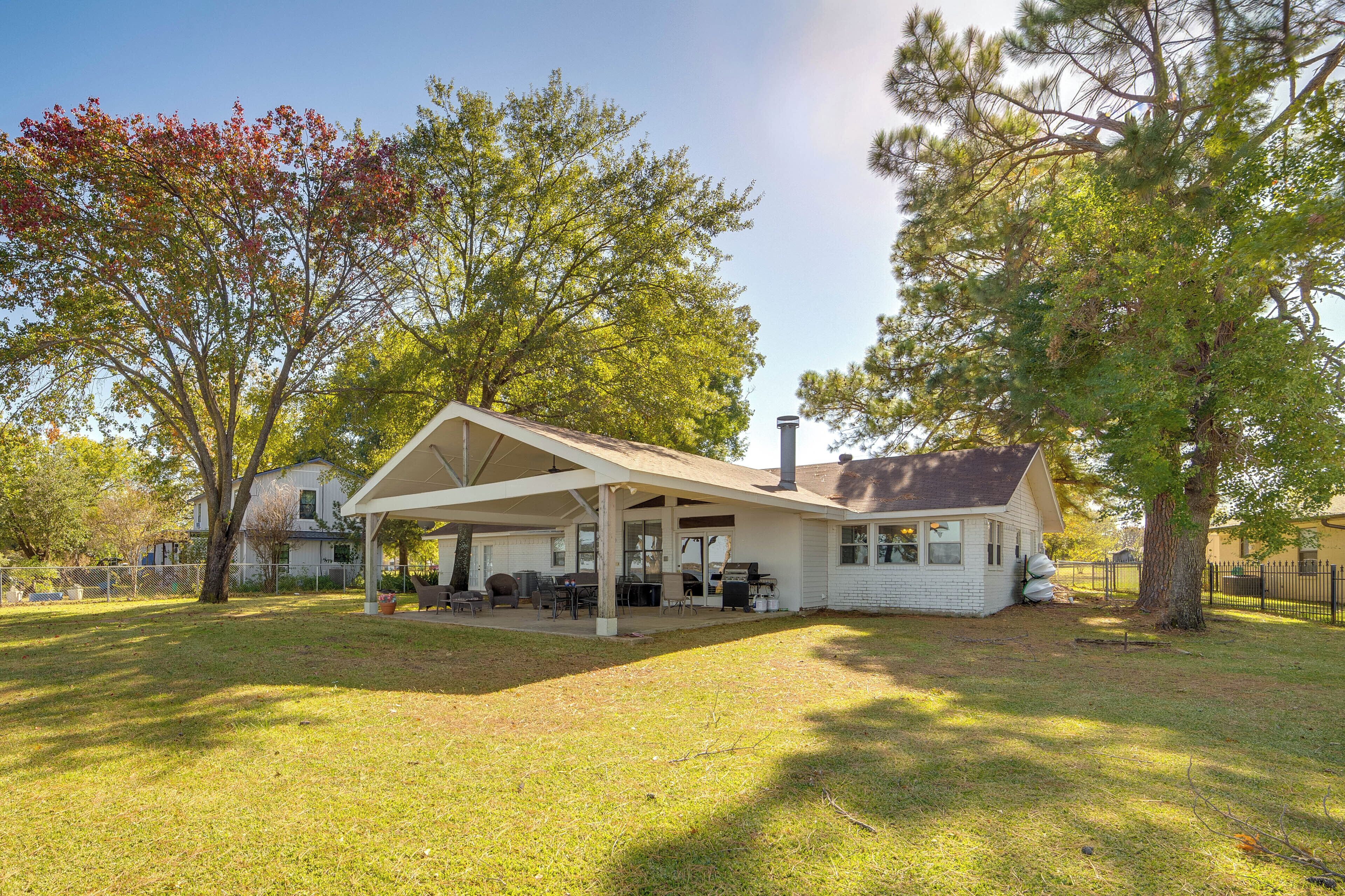 A house with a covered patio, a chimney, and a lawn.