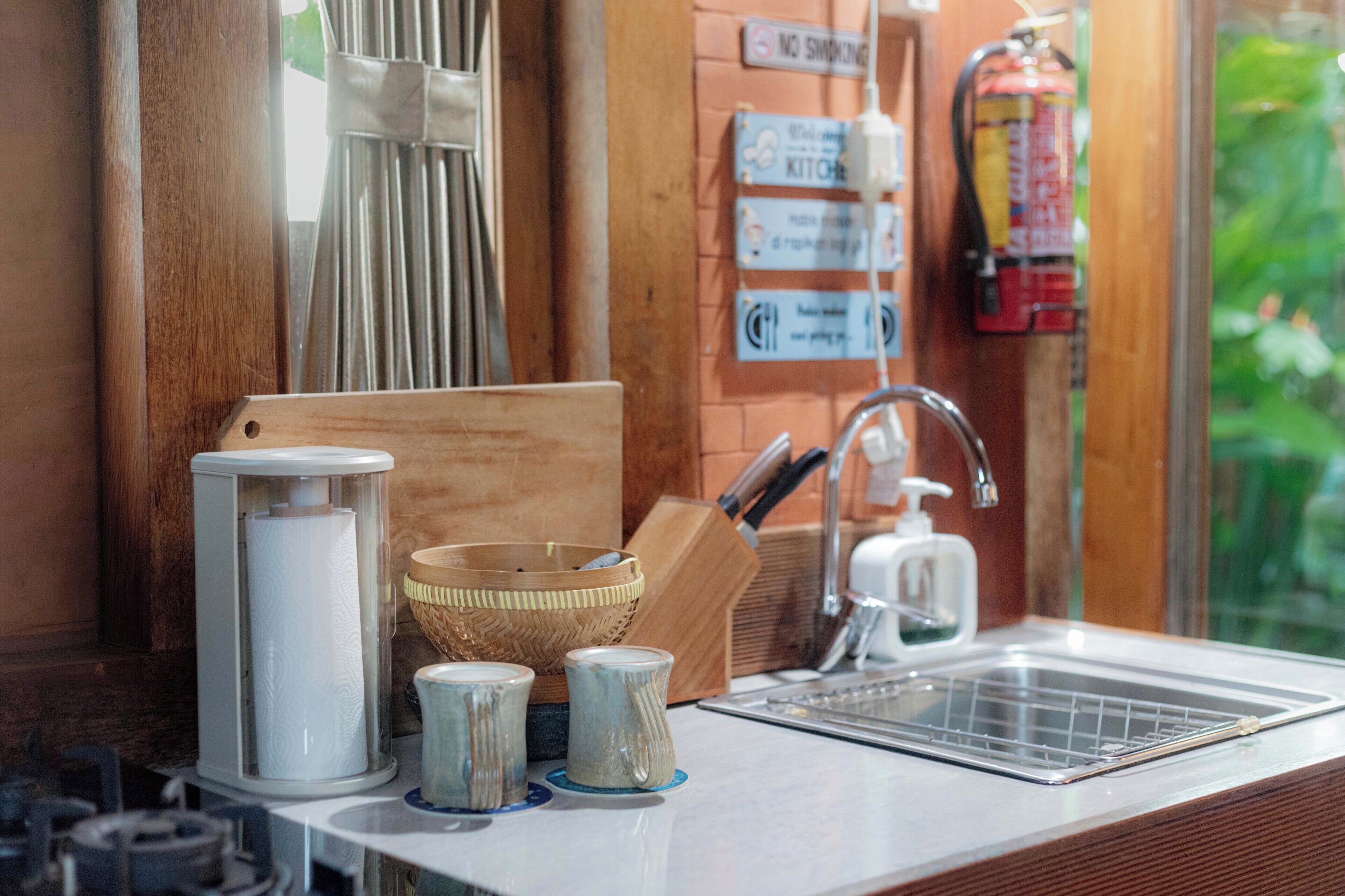A kitchen counter with a sink, a cutting board, a basket, and a roll of paper towels.