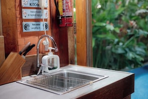 A kitchen area with a sink, a soap dispenser, and a knife block. - Ginza Bungalow  (Banguntapan)