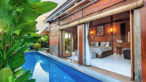 Een villa aan het zwembad met een privézwembad, een houten gevel en een slaapkamer met een bed en zithoek.