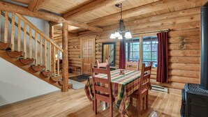 A wooden cabin interior with a dining table, chairs, a staircase, and a fireplace. - Along Big Wood River: Hailey Family Cabin w/ Yard (Hailey)