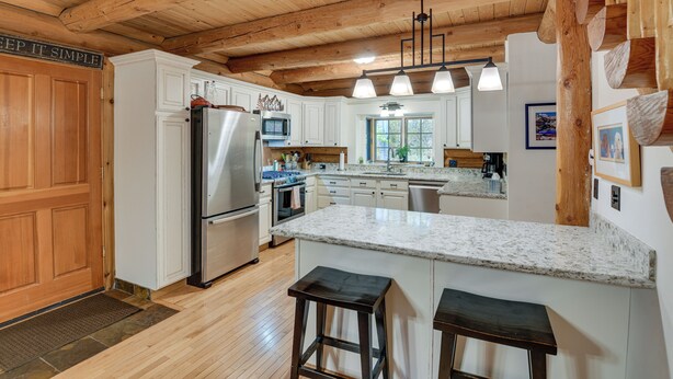 A modern kitchen with white cabinets, a stainless steel refrigerator, and a granite countertop. - Along Big Wood River: Hailey Family Cabin w/ Yard (Hailey)