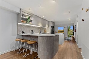 Una cocina moderna con una isla central, taburetes de bar y vistas al exterior.