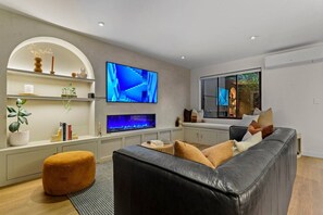 TV, fireplace, books - Spacious Coastal Luxe Home with Sea View & Parking (Auckland Hibiscus Coast)