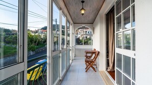 Ein Balkon mit Blick auf eine Wohngegend, einem Holztisch und einem Stuhl.