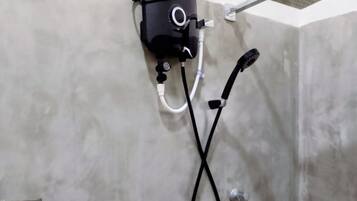 A shower area with a handheld showerhead, a control unit, and a metal shelf.