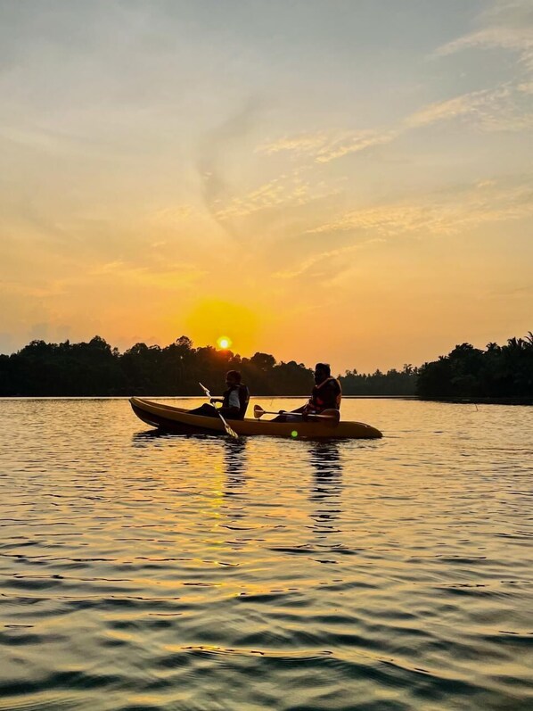 Two people in a canoe on a calm body of water during sunset. - Crush River Villa Hikkaduwa (Hikkaduwa)