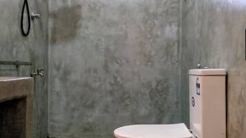 A bathroom with a toilet, a shower, and a window.