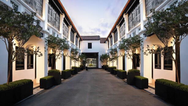 A symmetrical building with a central entrance, flanked by trees and planters, and a clear sky above. - Soori Penang (George Town)