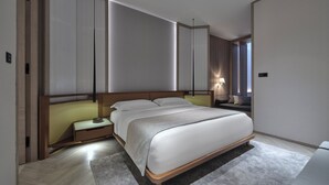 A modern hotel room with a large bed, bedside tables, a nightstand, and a window with a view. - Soori Penang (George Town)
