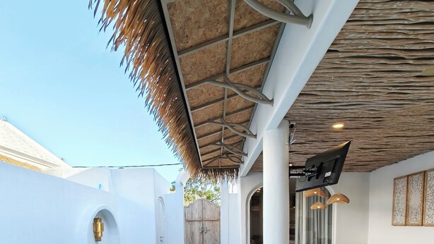 A pool area with a thatched roof, seating, and a view of the outside. - Villa Vinodayan Uluwatu (Ungasan)