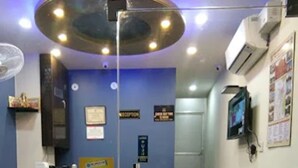 A reception area with a marble floor, a reception desk, a blue wall, and a staircase leading to an upper floor. - Hotel Deepak Residency (Jaipur)