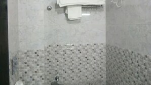 A small bathroom with a toilet, a towel rack, and a showerhead. - Hotel Deepak Residency (Jaipur)