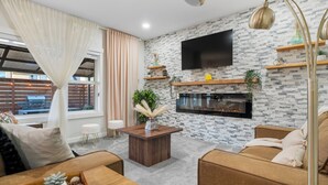 Een moderne woonkamer met een open haard, comfortabele zitplaatsen en een aan de muur bevestigde televisie.