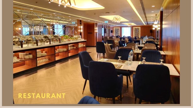 A restaurant with a buffet setup, wooden paneling, and modern lighting fixtures. - Al Hayat Hotel (Sharjah)