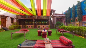 A courtyard with multiple seating areas, a staircase, and a building with traditional architecture. - Nimbal Dhani (Jaipur)
