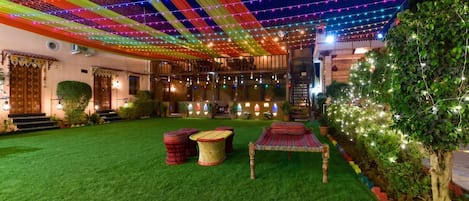 A courtyard with artificial grass, outdoor seating, and string lights.