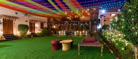 A courtyard with artificial grass, outdoor seating, and string lights.