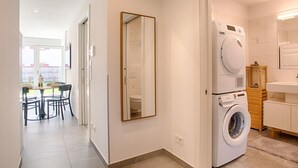 Una cucina moderna con un'isola centrale, un'area pranzo con tavolo e sedie, e un'ampia finestra che lascia entrare luce naturale.