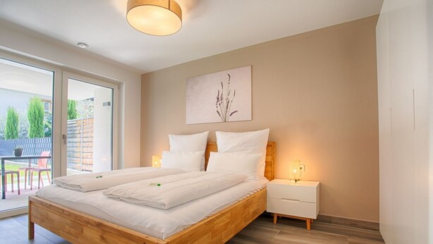 Una camera da letto moderna con un letto in legno, un comodino e una lampada a parete.