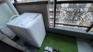 A compact room with a washing machine, a small green mat, and a pair of shoes. - 30sec walk to Tsutenkaku/1 stop to Namba Sta./AH23 (Ebisu Higashi Naniwa Ward,Osaka City)