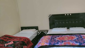 Una stanza con due letti, uno con testiera nera e l'altro con coperta fantasia.