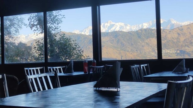 Un ristorante con ampie vetrate che si affaccia su montagne innevate.