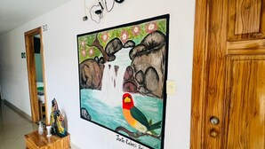 A hallway with a wooden door labeled 513, a tiled floor, and a wall-mounted painting of a bird and rocks.