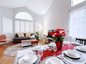Un coin repas avec une nappe rouge, des assiettes blanches et un grand arrangement floral rouge en guise de centre de table.