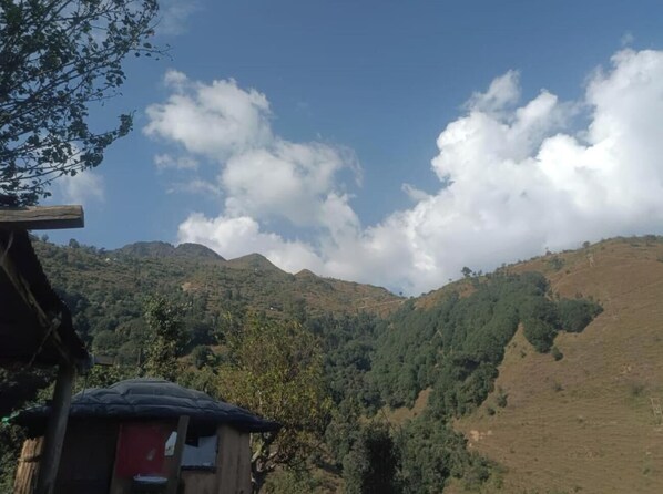 Paisaje rural con un pequeño edificio, posiblemente una casa de huéspedes, rodeado de colinas y árboles.