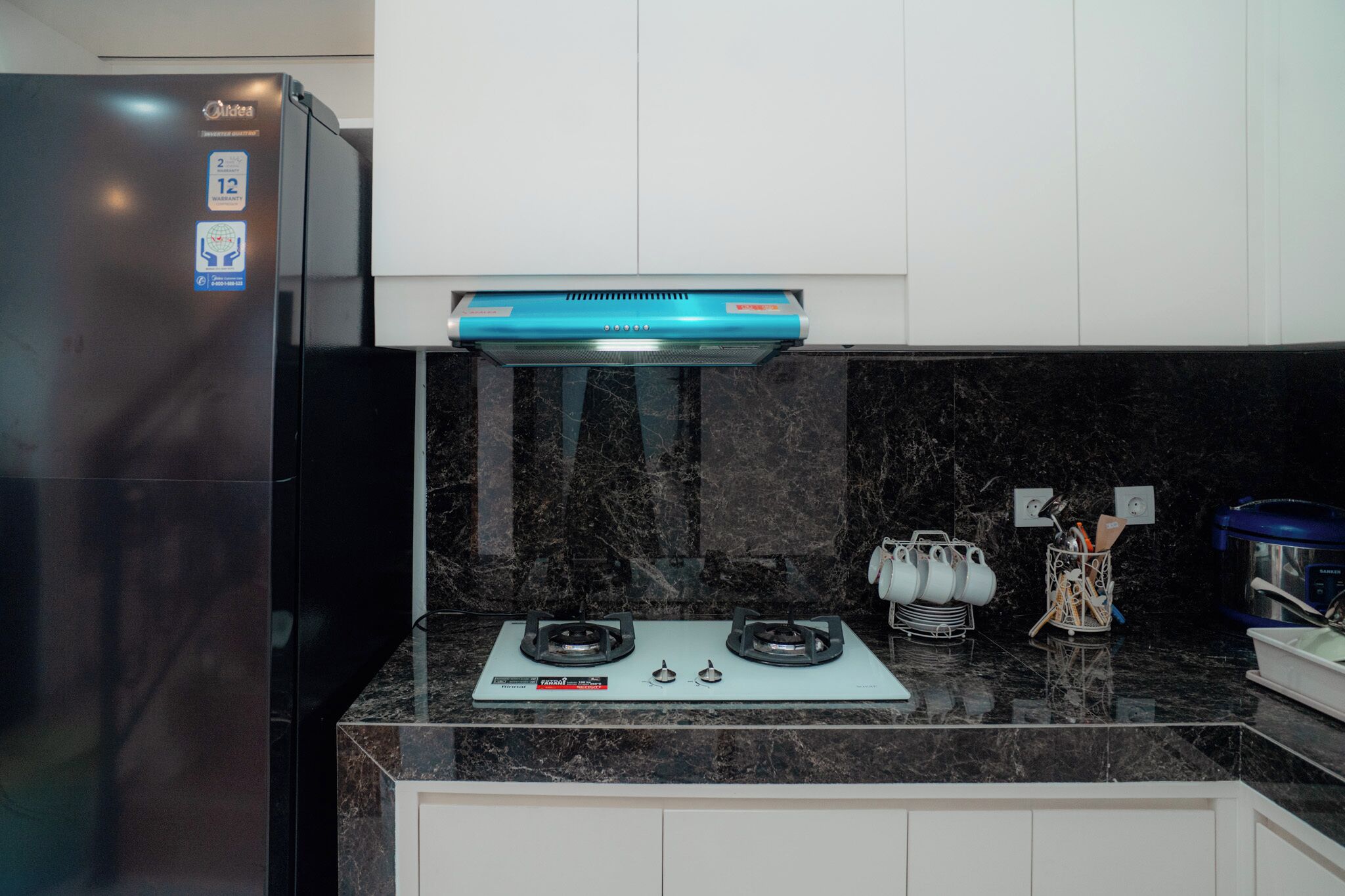 A kitchen with a black refrigerator, a gas stove, and a microwave.