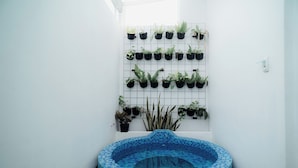 A small indoor pool with a tiled edge, surrounded by a white wall with a grid of potted plants. - Been View Homestay (Berbah)
