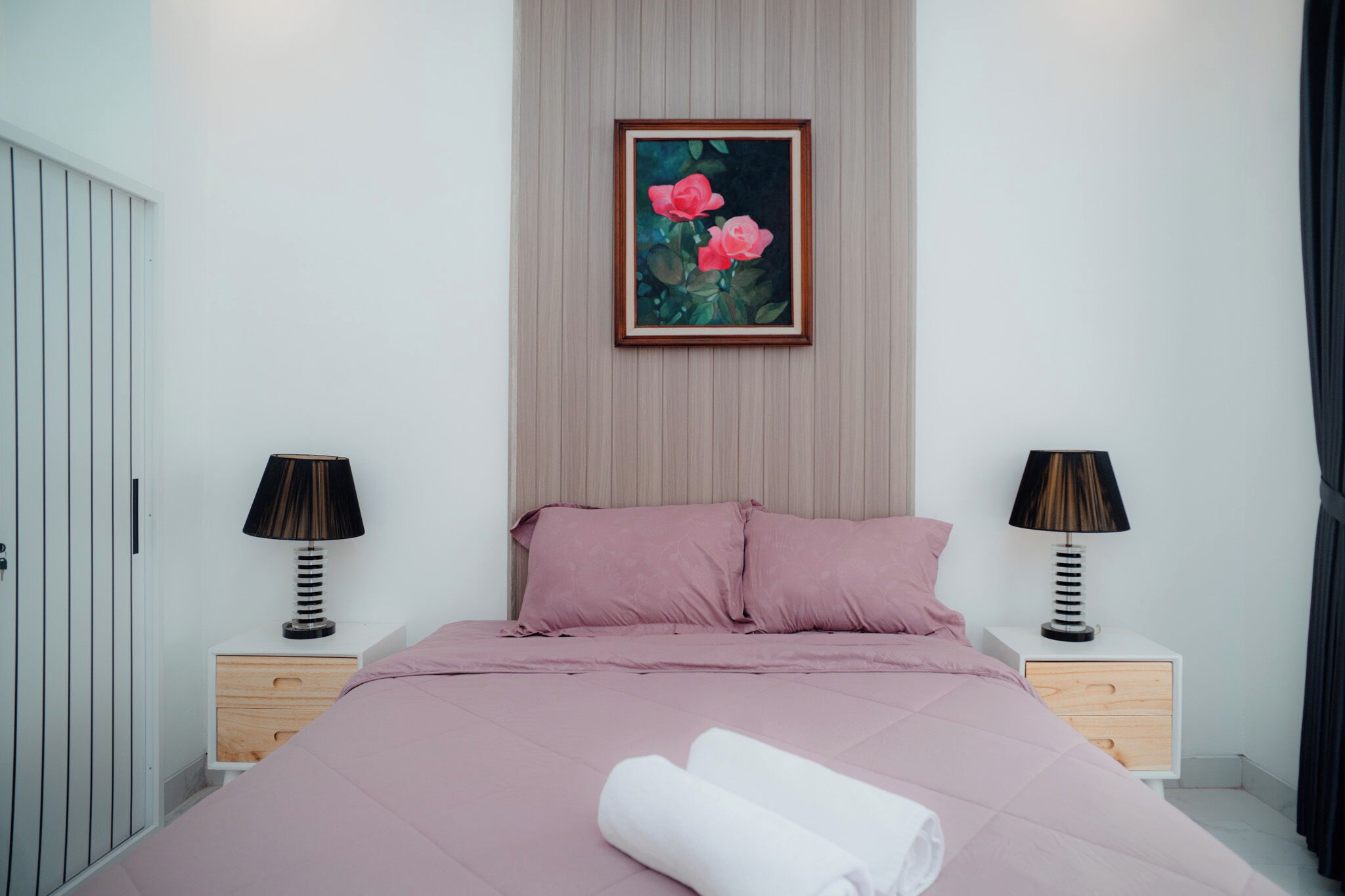 Ein Schlafzimmer mit einem Bett, zwei Nachttischen, einem Schrank und einem gerahmten Bild.