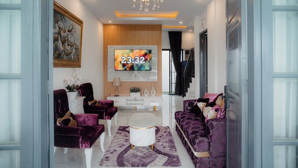 A modern living room with a flat-screen TV, a chandelier, and a staircase. - Been View Homestay (Berbah)