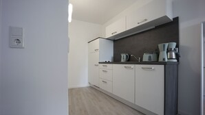 A modern kitchen with white cabinets, a dark countertop, and a coffee machine. - Vacation apartment "Rhön" (Bad Salzungen)