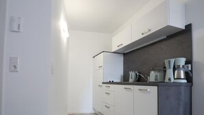 A modern kitchen with white cabinets, a dark countertop, and a coffee machine. - Vacation apartment "Rhön" (Bad Salzungen)