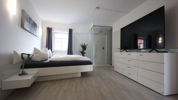 A modern bedroom with a bed, bedside table, TV, and a walk-in closet. - Vacation apartment "Rhön" (Bad Salzungen)