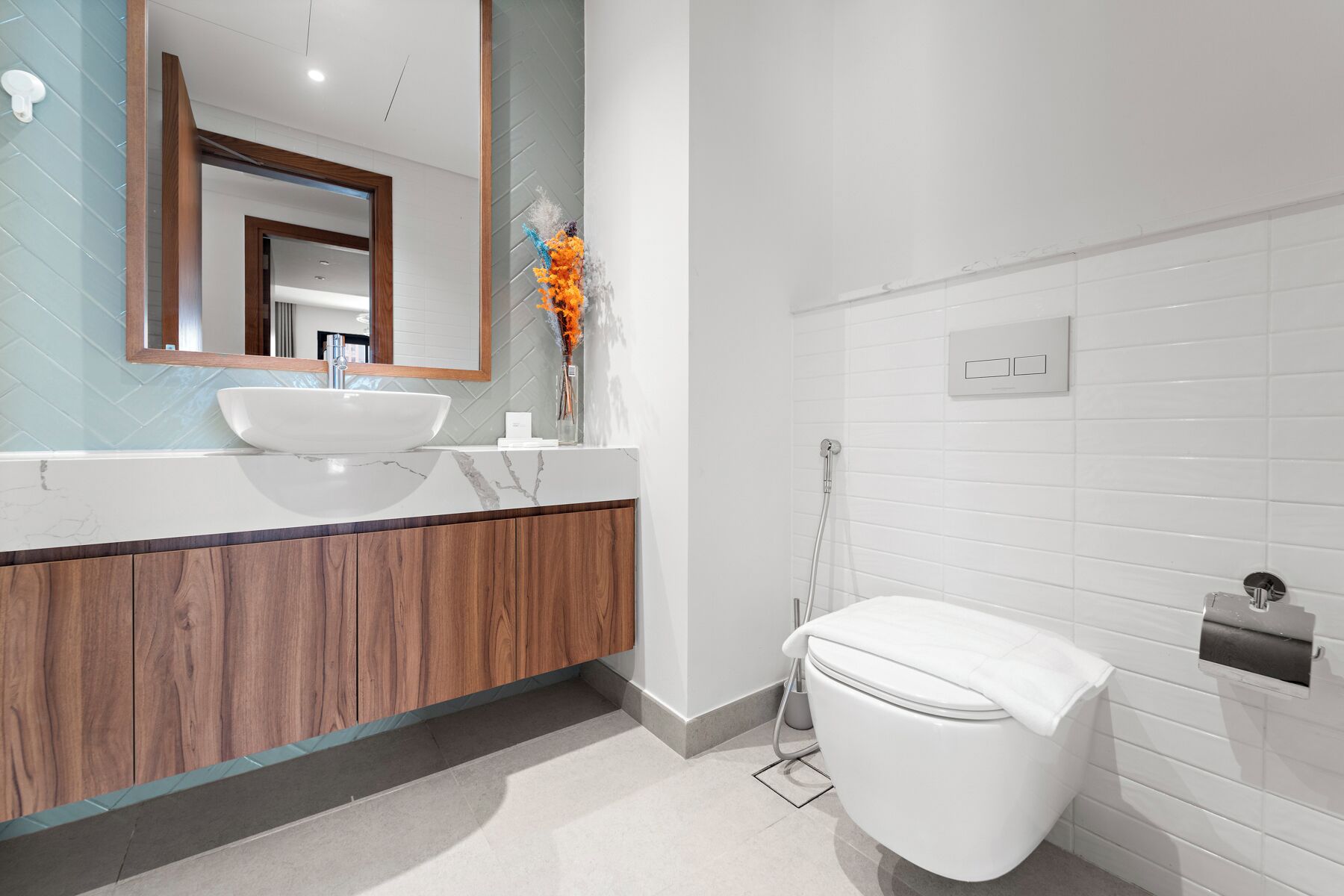 Une salle de bain moderne avec un lavabo blanc, un meuble-lavabo en bois, un grand miroir et un espace douche.