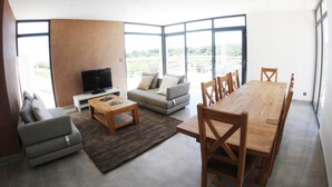 A modern living room with a sofa, coffee table, TV, and dining table with chairs. - Spacious Villa in Vagnas with Pool (Vagnas)