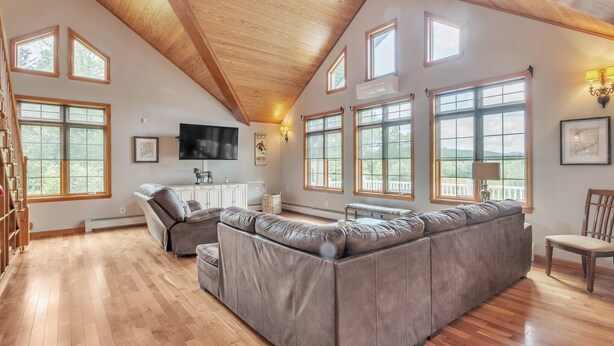 Amplia sala de estar con un sofá modular grande, piso de madera y múltiples ventanas que ofrecen luz natural.