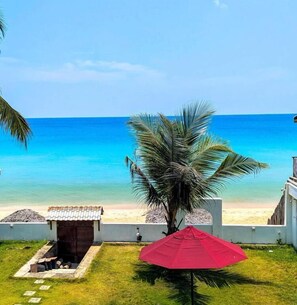 Une vue sur la plage avec un palmier et un parasol rouge.