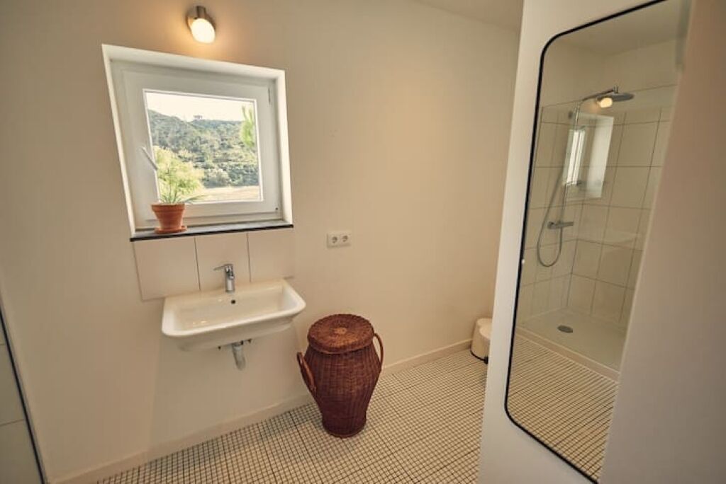 Ein Badezimmer mit Fenster, Waschbecken und Dusche.