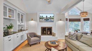 A spacious living area with a fireplace, a comfortable sofa, and a dining table. - Steps to Isle of Palms Beach w/ Porch Dining, Outdoor Shower & Open Living (Isle Of Palms)