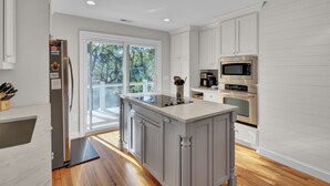 A modern kitchen with white cabinetry, stainless steel appliances, and a large island. - Steps to Isle of Palms Beach w/ Porch Dining, Outdoor Shower & Open Living (Isle Of Palms)