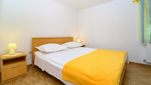 A single bed with a wooden headboard, two bedside lamps, a nightstand, and a yellow throw blanket. - Beachfront apartment fully equipped with outdoor garden space, parking included. (Okrug Gornji)
